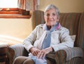 Happy elderly woman smiling sitting on sofa at home enjoying retirement Royalty Free Stock Photo