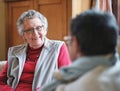 Happy elderly woman talking to friend sitting on sofa in retirement home having conversation Royalty Free Stock Photo