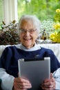 Happy Elderly woman using a tablet looking at the camera and laughing Royalty Free Stock Photo