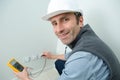 Happy electrician checking voltage in electrical wall socket