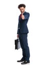 Happy elegant businessman smiling, holding suitcase and making thumbs up gesture Royalty Free Stock Photo