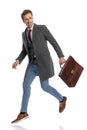 Happy elegant man with suitcase looking to side and leaping up Royalty Free Stock Photo