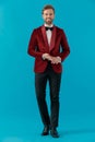 Happy elegant model wearing red velvet tuxedo and touching palms Royalty Free Stock Photo