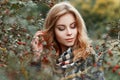 Happy elegant pretty young woman with vintage checkered scarf in luxurious warm coat is standing near a tree in the forest. Royalty Free Stock Photo