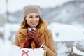 elegant middle aged woman in camel coat with shopping bags and cup of soy latte outside in the city in winter