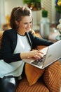 Happy elegant woman doing research while sitting on sofa