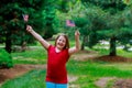 Happy elementary age little girl smiles while holding American flag in her front yard on the Fourth of July. Independence Day, Fla Royalty Free Stock Photo
