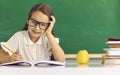 Happy elementary school girl student in eyeglasses sitting at desk and studying Royalty Free Stock Photo