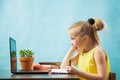 Happy elementary student girl homeschooling on laptop online by internet. Royalty Free Stock Photo