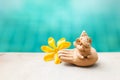 Happy elephant clay sitting on hand sculpture with yellow flower over blurred blue water background