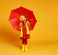 Happy emotional cheerful child girl laughing with red umbrella on yellow background