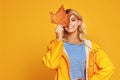 Happy emotional girl with autumn leaves on colored yellow background