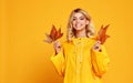 Happy emotional girl with autumn leaves on colored yellow background