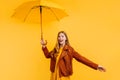 Happy emotional girl in a yellow dress and autumn jacket, laughing and having fun with a yellow umbrella on an yellow background, Royalty Free Stock Photo