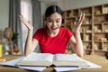 Happy emotional smart pretty young asian lady student with open mouth screaming with joy at table with book