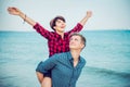 Happy emotional woman with raised up hands on young man`s back. Couple enjoying each other, having fun on the beach. Date, love s Royalty Free Stock Photo