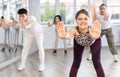 Happy emotional young female dancer rehearsing popping techniques during group workout in modern street dance studio Royalty Free Stock Photo