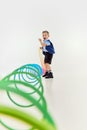 Happy emotions. Boy, child in classical retro clothes playing with slinky toy over grey studio background. Concept of