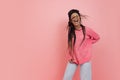 Studio shot of young excited girl with afro hairdo in casual style outfit having fun isolated on pink background Royalty Free Stock Photo