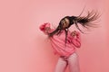 Studio shot of young excited girl with afro hairdo in casual style outfit having fun isolated on pink background Royalty Free Stock Photo