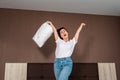 Happy emotions. A young woman sings and cheers with a pillow in her hands. Indoor. Bottom view