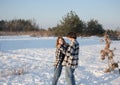 Happy enamored teenage girl and a guy, about 16-17 years old, in plaid shirts and jeans, are standing in snow
