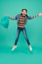 Happy energetic child jump with school bag in casual fashion style blue background, childhood