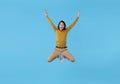 Happy energetic young Asian man jumping in mid-air isolated on blue background Royalty Free Stock Photo