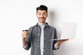 Happy energized guy drinking coffee and working on laptop, got energy from drink, standing on white background Royalty Free Stock Photo