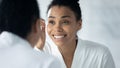 Happy engaged Black millennial girl in bathrobe plucking eyebrows Royalty Free Stock Photo