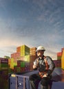 Happy Engineer sit in stack containers. His happy drinking coffee after successful work. Photo with 3d render composing Royalty Free Stock Photo