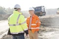 Happy engineer talking to colleague at construction site on sunny day Royalty Free Stock Photo