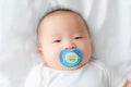 Happy and enjoy Portrait of a newborn Asian baby boy on the bed ,a dummy in his mouth, Charming Royalty Free Stock Photo