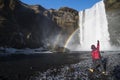 Happy and enjoy road trip with hand up at big Skogafoss waterfall Iceland and double rainbow in sunnyday in winter. Royalty Free Stock Photo