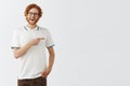 Happy enthusiastic handsome redhead guy with long beard in glasses and casual outfit pointing right with forefinger and