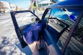 Happy entrepreneur opening his car door and inspecting the interior of his car while being parked next to a busy city boulevard