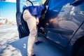 Happy entrepreneur opening his car door and inspecting the interior of his car while being parked next to a busy city boulevard