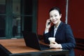 Serious business woman beautiful young blond woman talking on the mobile cell phone working on a laptop pc computer in restaurant Royalty Free Stock Photo