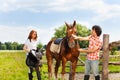 Happy equestrians preparing their horse for riding Royalty Free Stock Photo