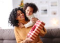 Cheerful ethnic family: happy child and mother congratulate each other at Christmas