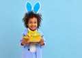 Happy ethnic child boy with easter eggs and bunny ears on blue background Royalty Free Stock Photo