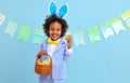 Happy ethnic child boy with easter eggs and bunny ears on blue background Royalty Free Stock Photo