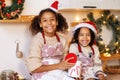 Happy ethnic children on Christmas eve,   girl and boy eat cookies that they baked together in cozy kitchen at home Royalty Free Stock Photo