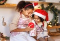 Happy ethnic children on Christmas eve,   girl and boy eat cookies that they baked together in cozy kitchen at home Royalty Free Stock Photo