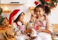 Happy ethnic children on Christmas eve,   girl and boy eat cookies that they baked together in cozy kitchen at home Royalty Free Stock Photo