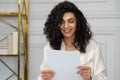 Happy ethnic woman with curly black hair reads a letter with good news, a great offer, an opportunity to get a job Royalty Free Stock Photo
