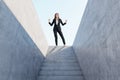 Happy european businesswoman celebrating success on top of abstract concrete stairs with sunlight. Growth concept