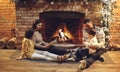 Happy family parents with two kids relaxing by fireplace during winter holidays in cozy countryhouse Royalty Free Stock Photo