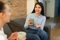 Happy european friends talking and drinking tea, sitting on sofa, enjoying communication and free time at home Royalty Free Stock Photo