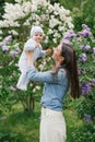 Happy European mother lifts up her little smiling son in her arms in the spring on a walk in the park Royalty Free Stock Photo